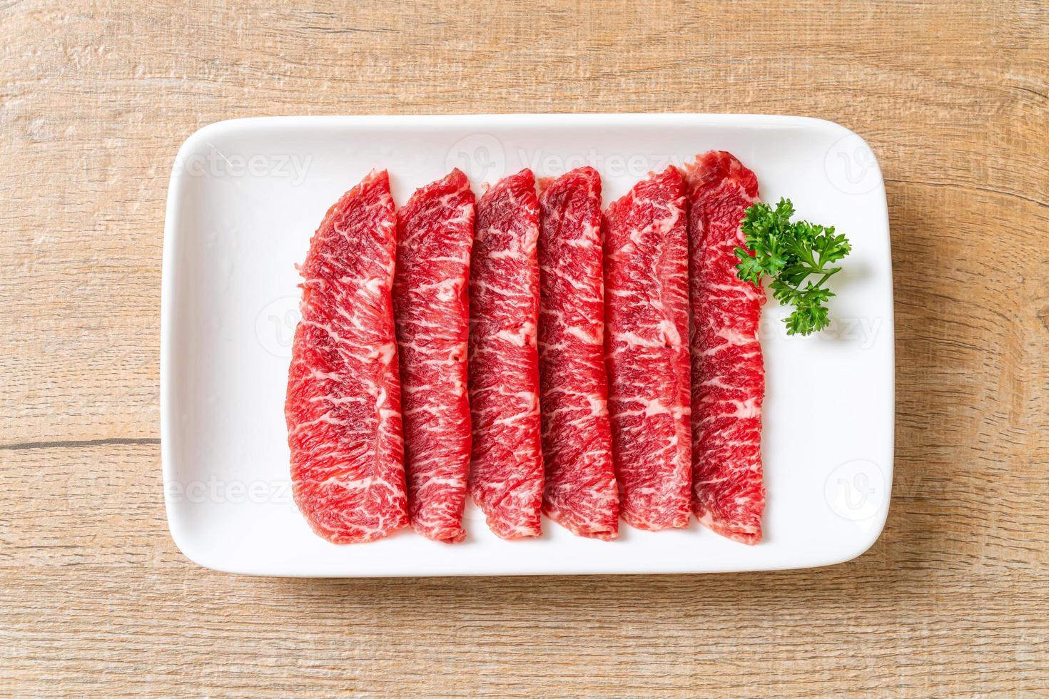 Carne fresca cruda en rodajas con textura de mármol servida para sukiyaki y shabu o yakiniku foto