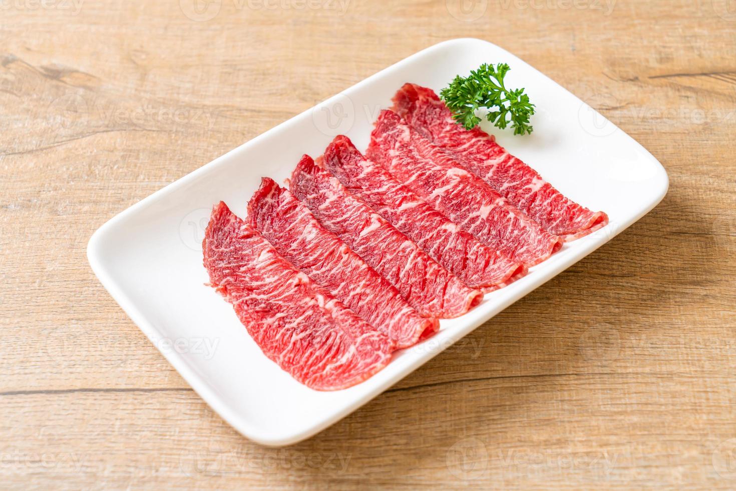 Carne fresca cruda en rodajas con textura de mármol servida para sukiyaki y shabu o yakiniku foto