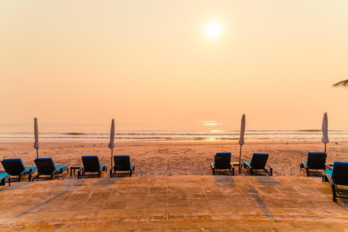 Silla de playa sombrilla con palmera y playa al amanecer - concepto de vacaciones y vacaciones foto