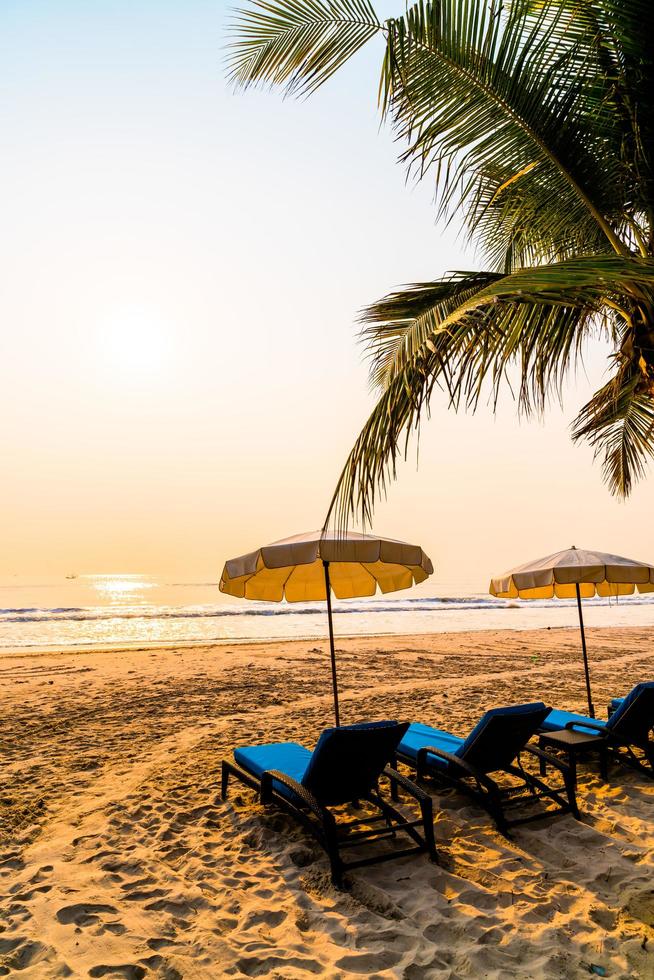 Umbrella beach chair with palm tree and sea beach at sunrise time - vacation and holiday concept photo