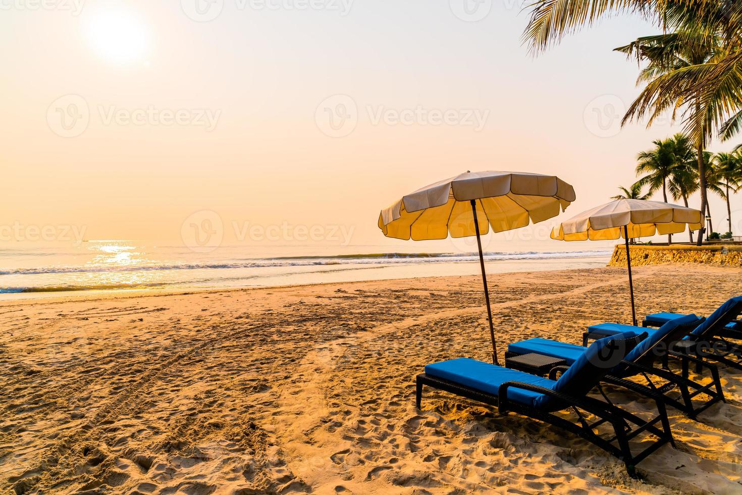 Silla de playa sombrilla con palmera y playa al amanecer - concepto de vacaciones y vacaciones foto