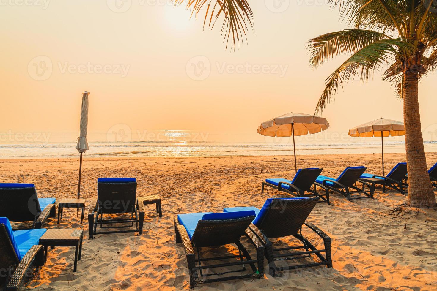 Silla de playa sombrilla con palmera y playa al amanecer - concepto de vacaciones y vacaciones foto