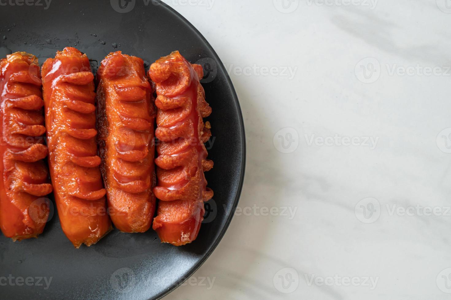 Deep-fried sausage skewer on black plate photo