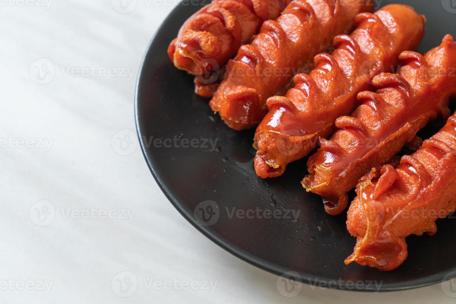 Deep-fried sausage skewer on black plate photo
