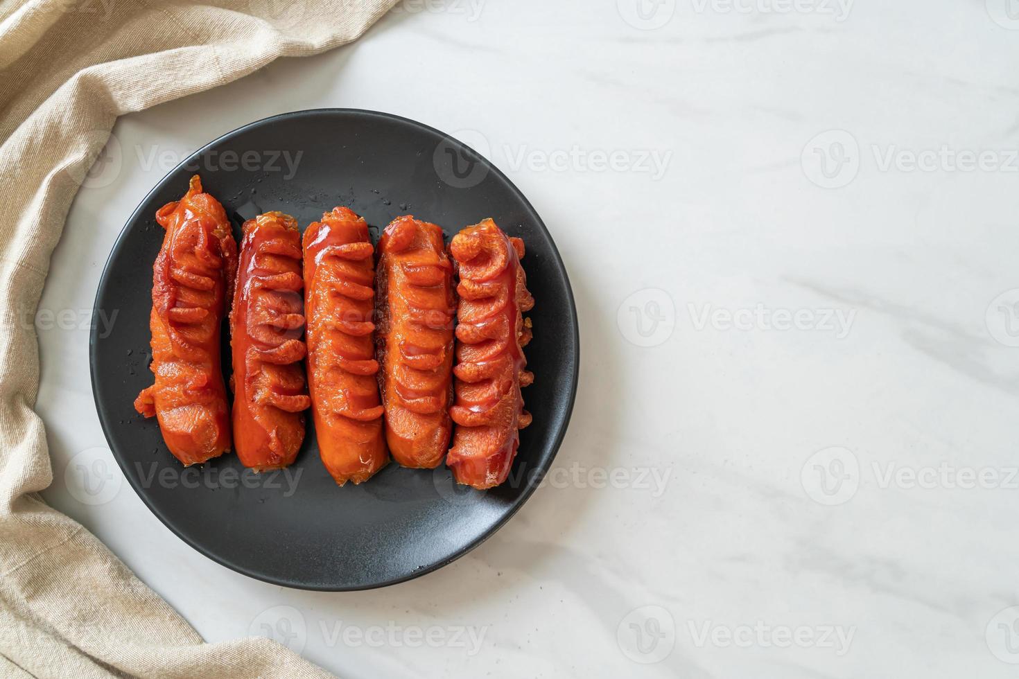 Deep-fried sausage skewer on black plate photo