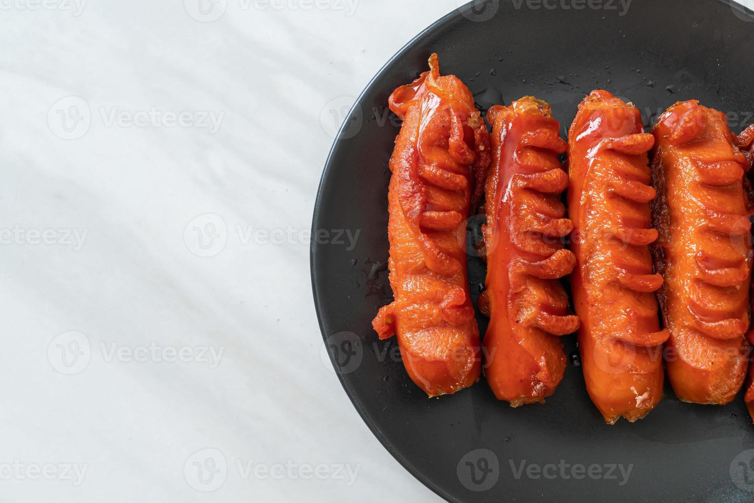 Deep-fried sausage skewer on black plate photo