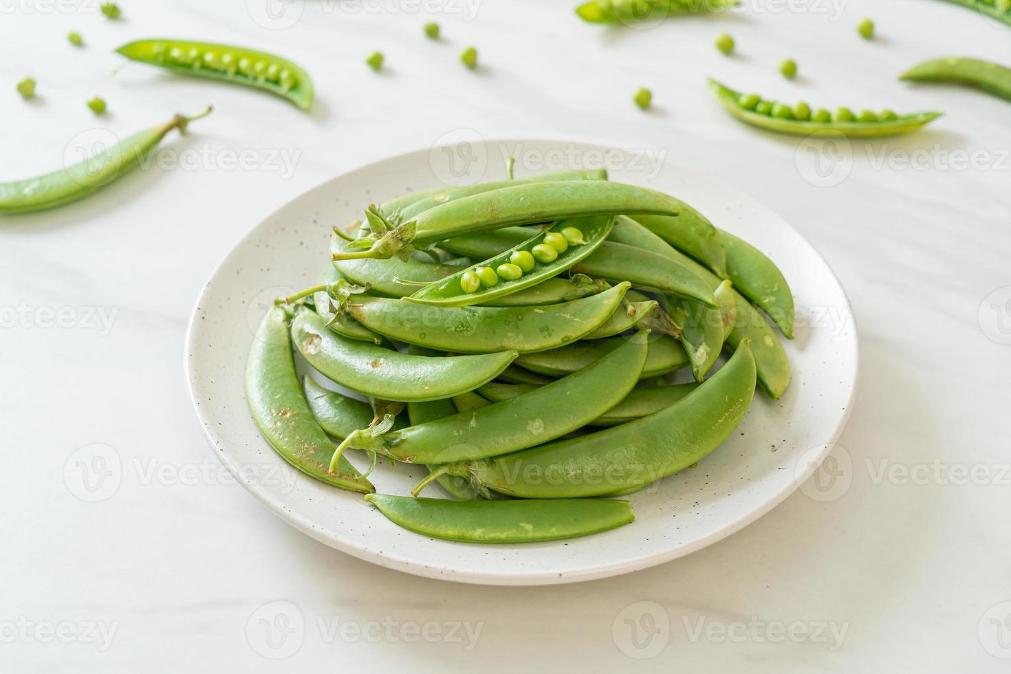 Guisantes verdes dulces frescos en la placa blanca. foto