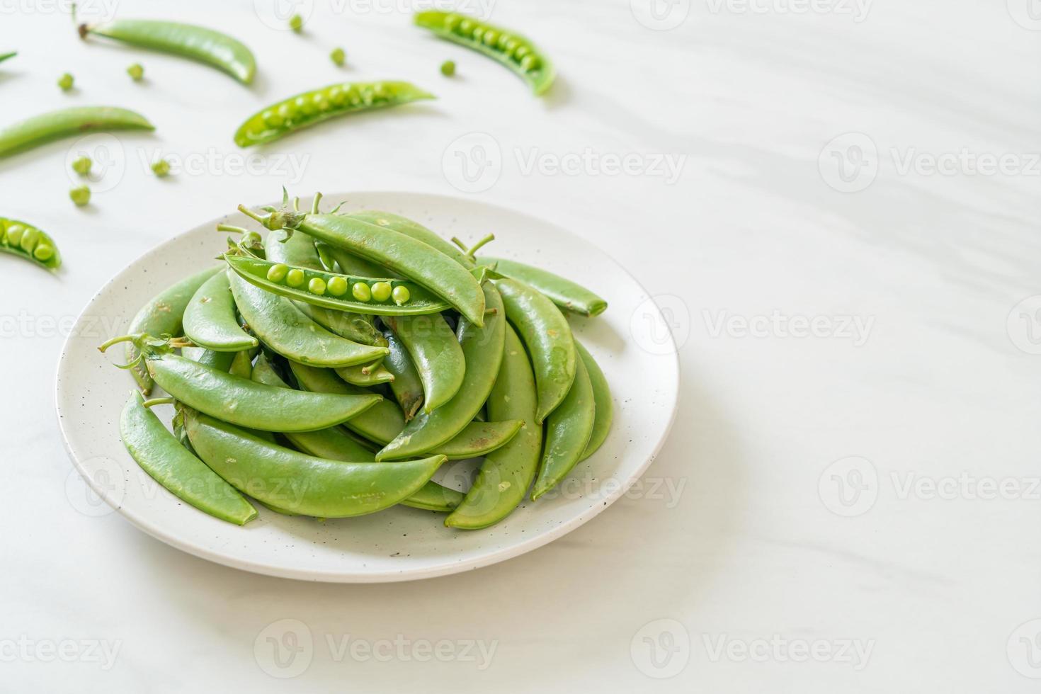 Guisantes verdes dulces frescos en la placa blanca. foto