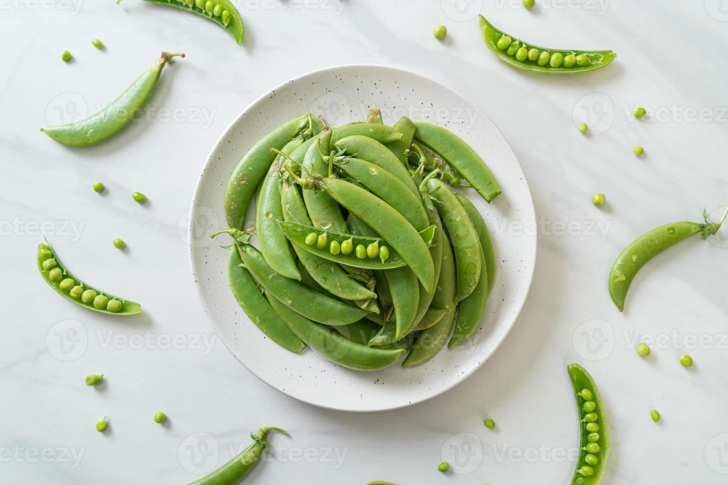 Guisantes verdes dulces frescos en la placa blanca. foto