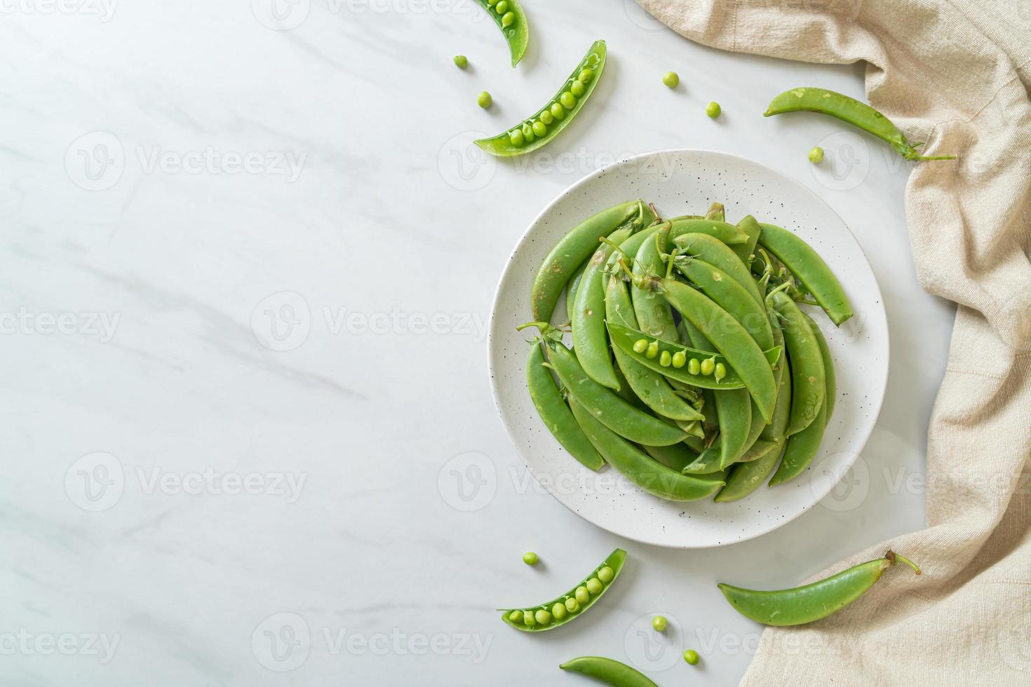 Guisantes verdes dulces frescos en la placa blanca. foto