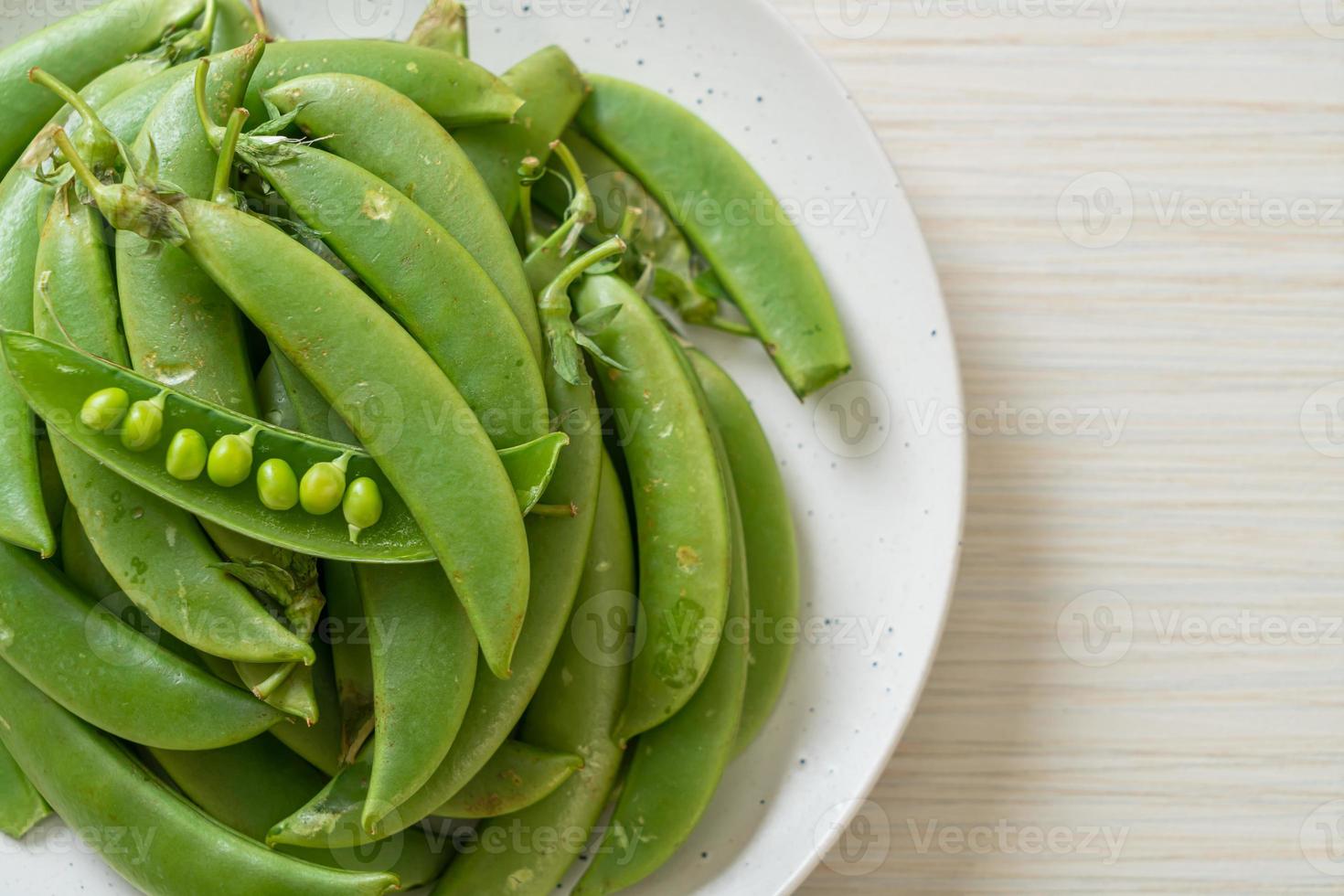 Guisantes verdes dulces frescos en la placa blanca. foto