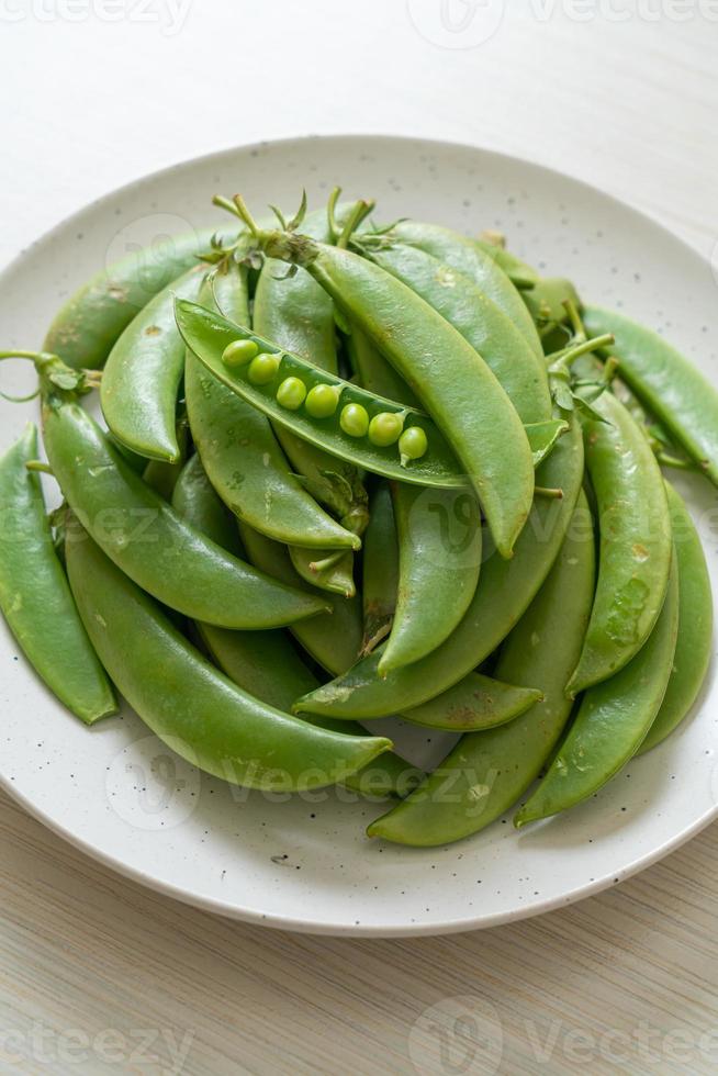 Guisantes verdes dulces frescos en la placa blanca. foto