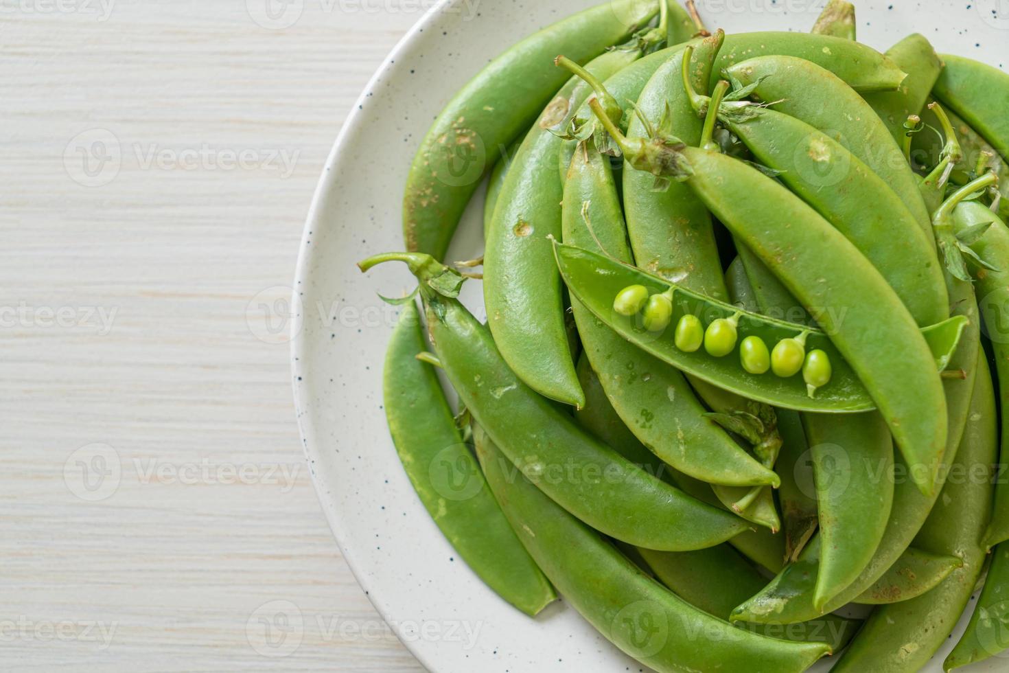 Fresh sweet green peas on white plate photo