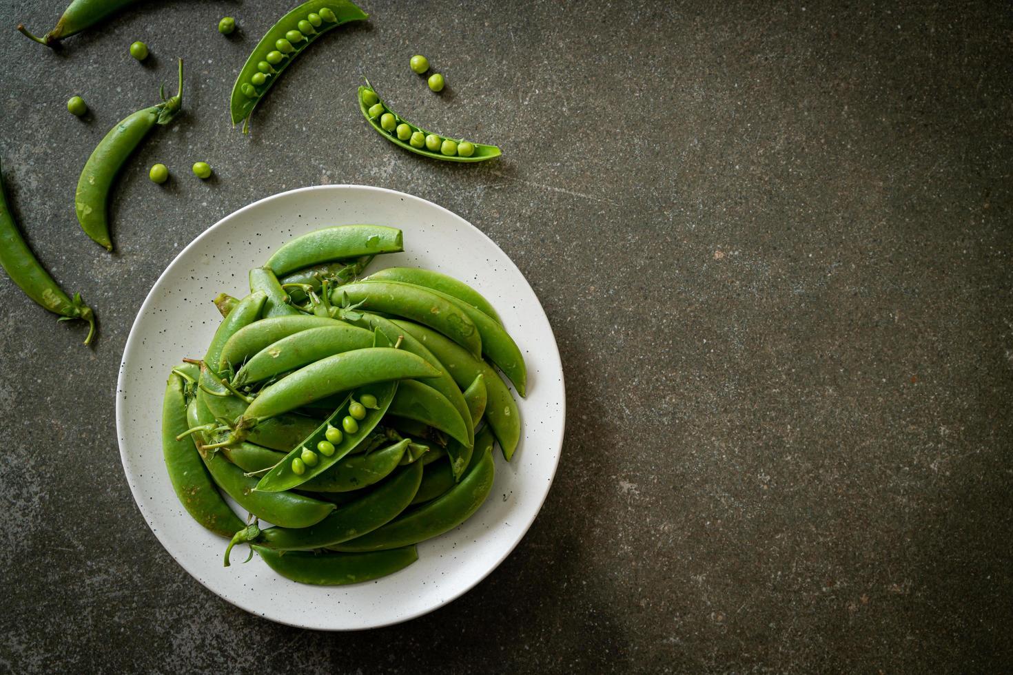 Guisantes verdes dulces frescos en la placa blanca. foto