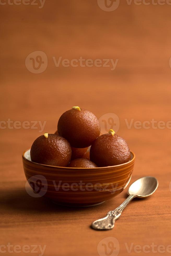 gulab jamun en un tazón sobre fondo de madera. postre indio o plato dulce. foto