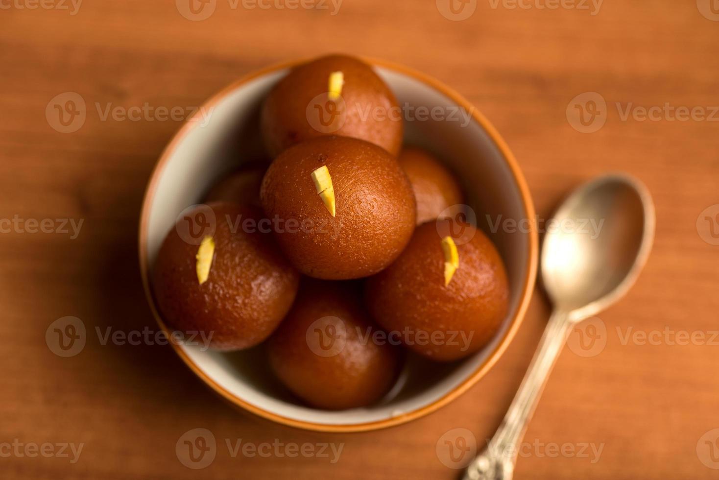 gulab jamun en un tazón sobre fondo de madera. postre indio o plato dulce. foto