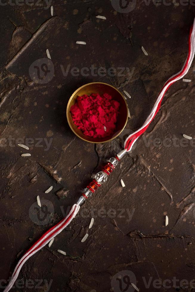 Fondo de raksha bandhan con un elegante rakhi, granos de arroz y kumkum. una pulsera tradicional india que es un símbolo del amor entre hermanos y hermanas. foto