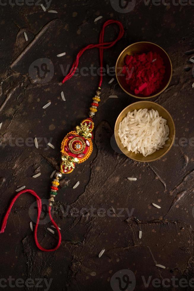 Raksha Bandhan background with an elegant Rakhi, Rice Grains and Kumkum. A traditional Indian wrist band which is a symbol of love between Brothers and Sisters. photo