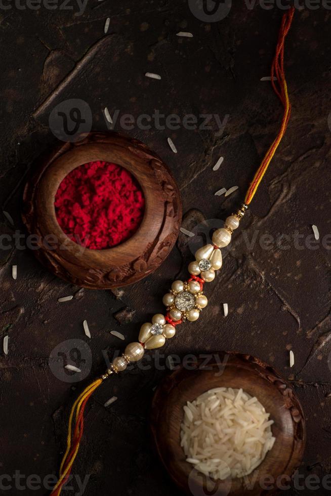 Fondo de raksha bandhan con un elegante rakhi, granos de arroz y kumkum. una pulsera tradicional india que es un símbolo del amor entre hermanos y hermanas. foto