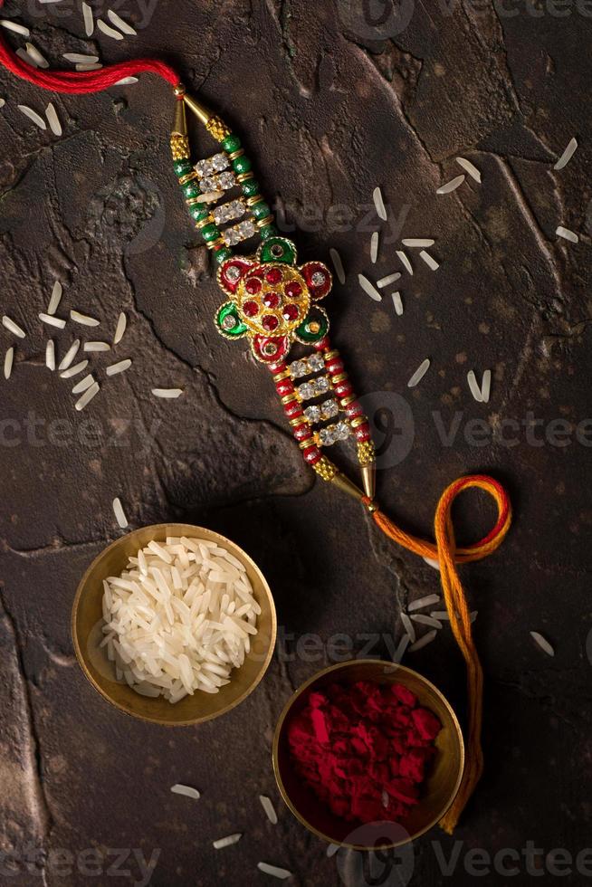 Fondo de raksha bandhan con un elegante rakhi, granos de arroz y kumkum. una pulsera tradicional india que es un símbolo del amor entre hermanos y hermanas. foto