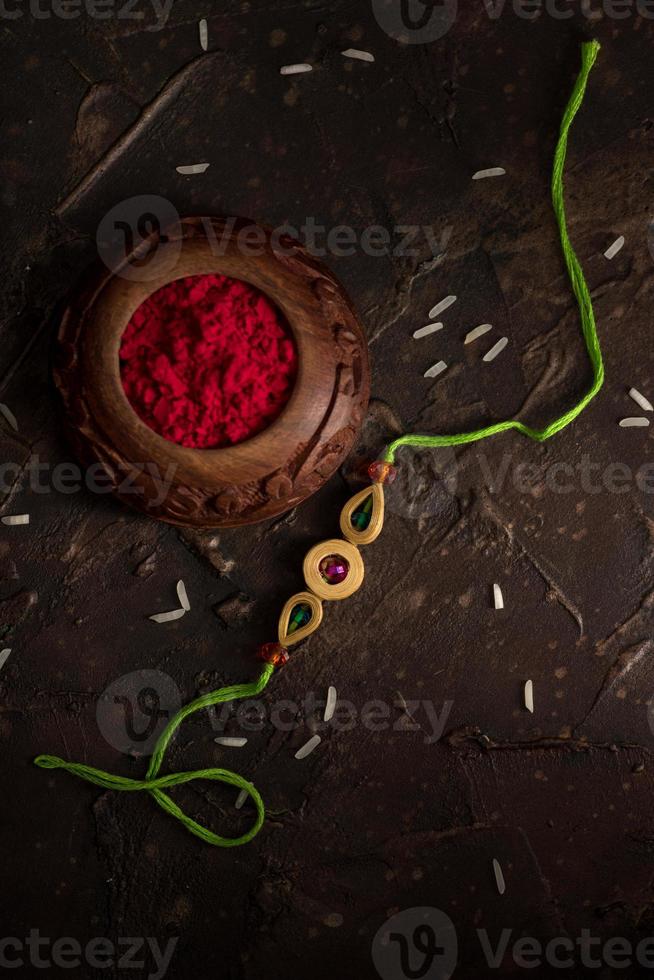 Fondo de raksha bandhan con un elegante rakhi, granos de arroz y kumkum. una pulsera tradicional india que es un símbolo del amor entre hermanos y hermanas. foto