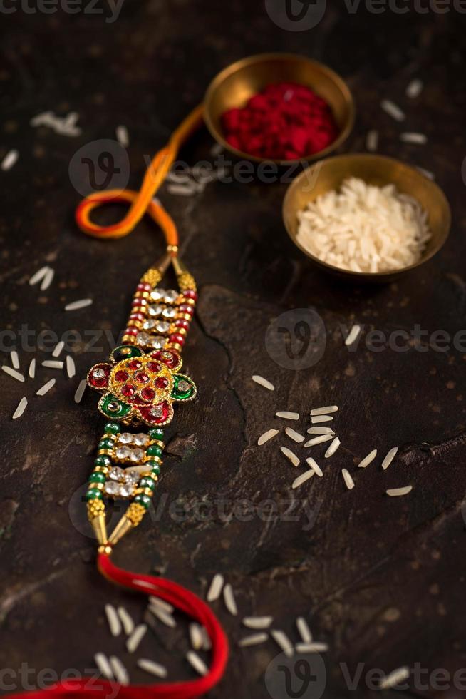 Fondo de raksha bandhan con un elegante rakhi, granos de arroz y kumkum. una pulsera tradicional india que es un símbolo del amor entre hermanos y hermanas. foto