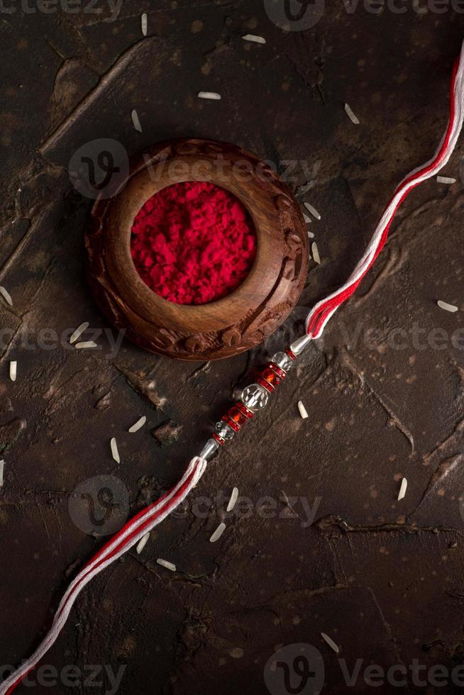 Raksha Bandhan background with an elegant Rakhi, Rice Grains and Kumkum. A traditional Indian wrist band which is a symbol of love between Brothers and Sisters. photo