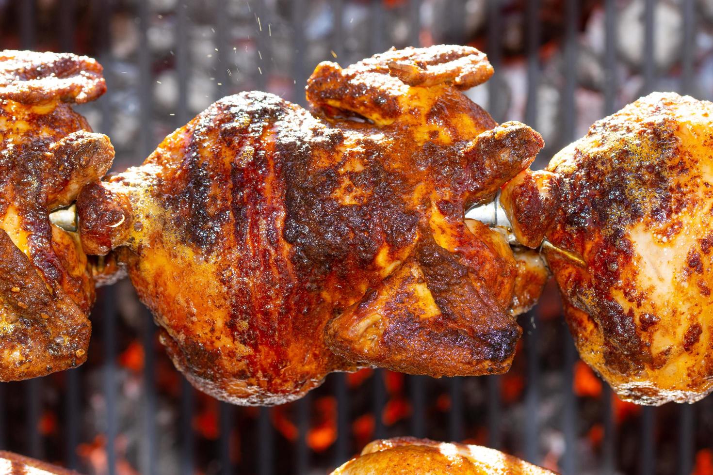 Pollos asados en asador a la parrilla sobre el fuego de una gran barbacoa foto