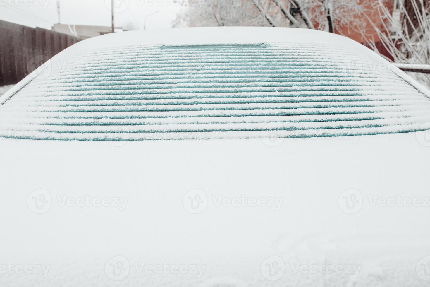 Ice melts on the rear window of the car - electric window heating with contact strips photo