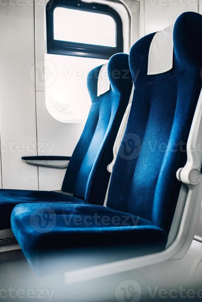 una fila de sillas suaves con respaldo alto junto a la ventana en el vagón del tren: un viaje cómodo foto