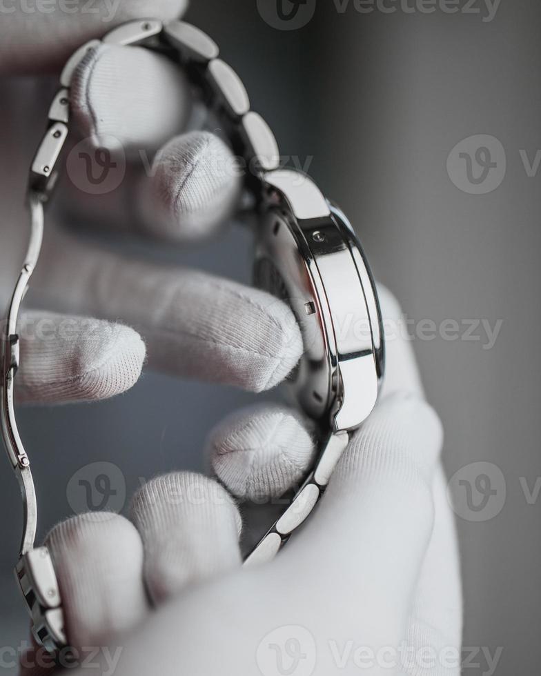 un vendedor con guantes blancos muestra un costoso reloj suizo longines: un cronómetro de pulsera masculino para las vacaciones como regalo foto