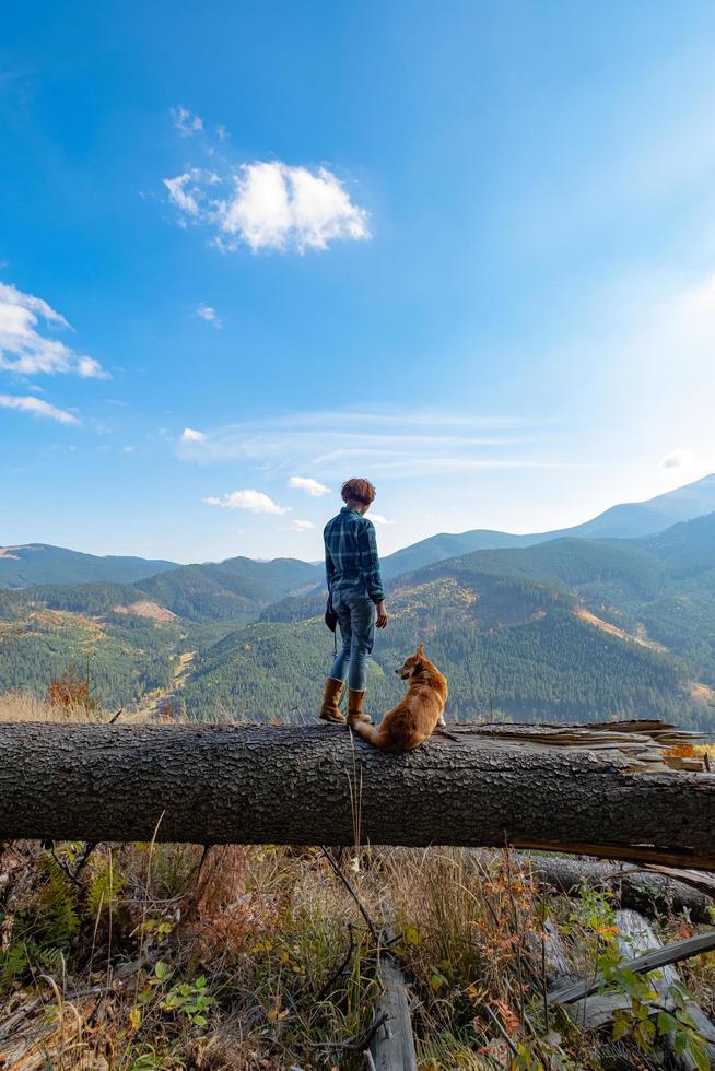 Viajero joven con perro corgi en las montañas foto