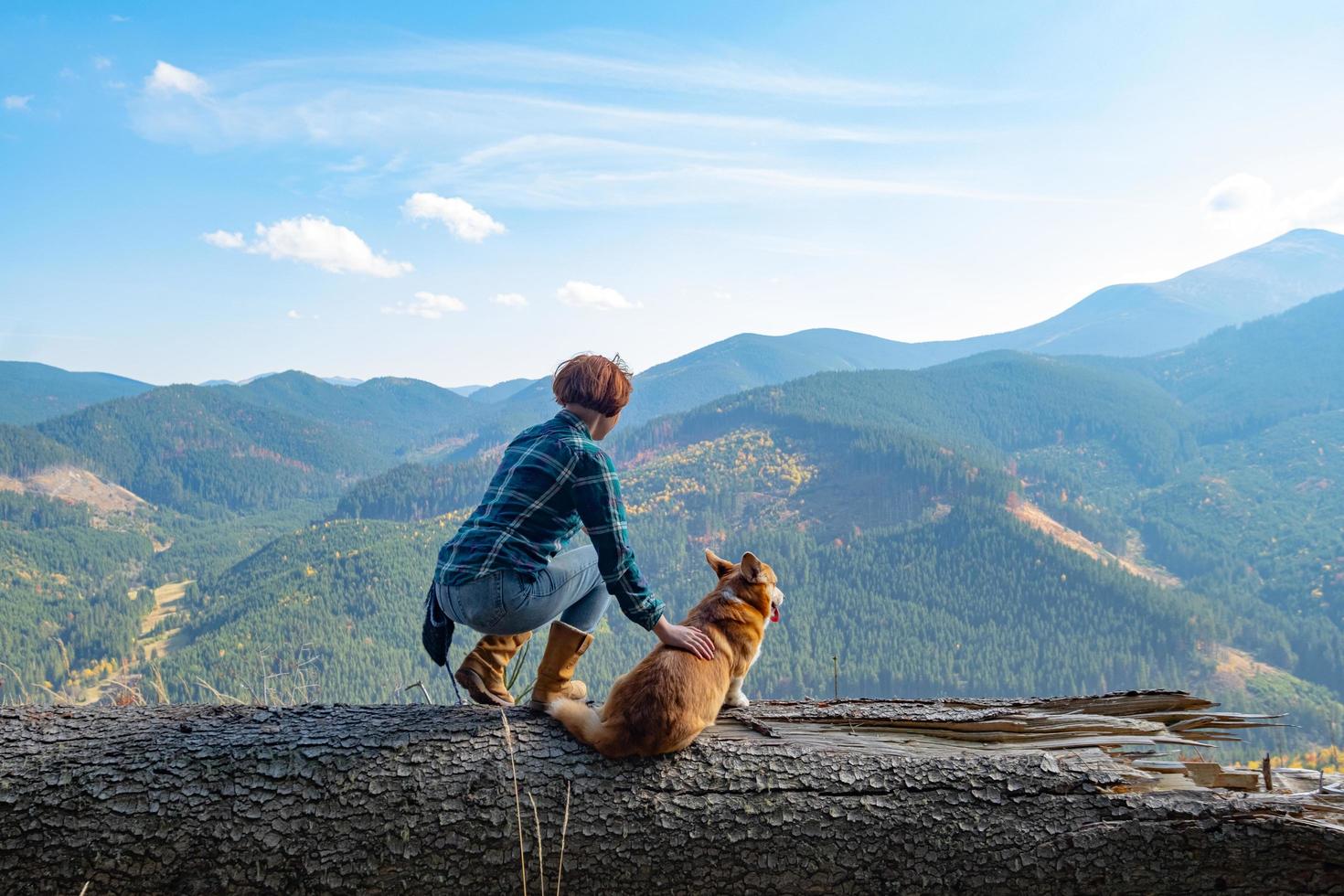 Viajero joven con perro corgi en las montañas foto