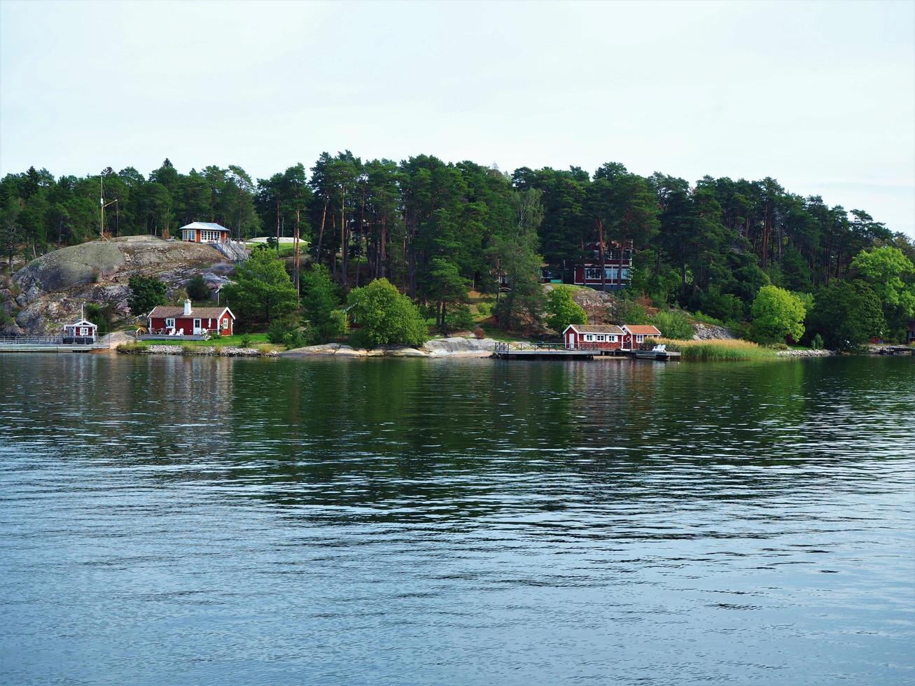 Isla boscosa en el archipiélago de Estocolmo, Suecia, con una costa rocosa y residencias de verano foto