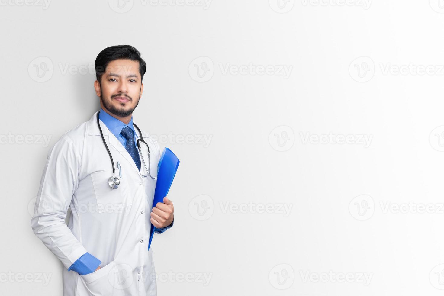 Doctor en bata de laboratorio sosteniendo el expediente del paciente o notas médicas mirando a la cámara, aislado sobre fondo blanco. foto