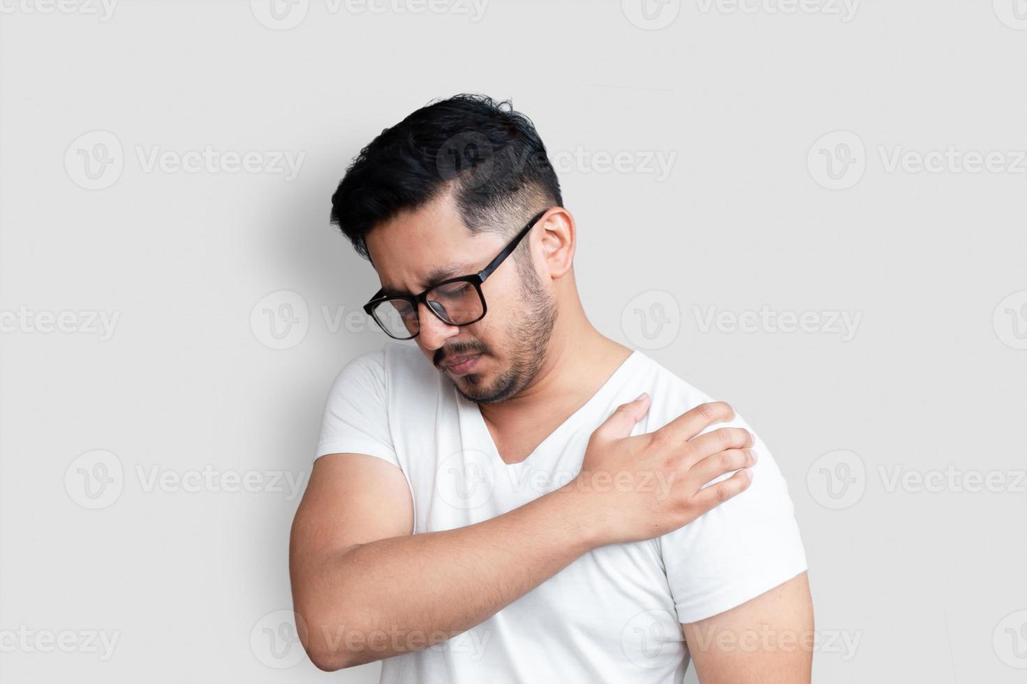 Handsome young man with black glasses with shoulder pain on white background photo