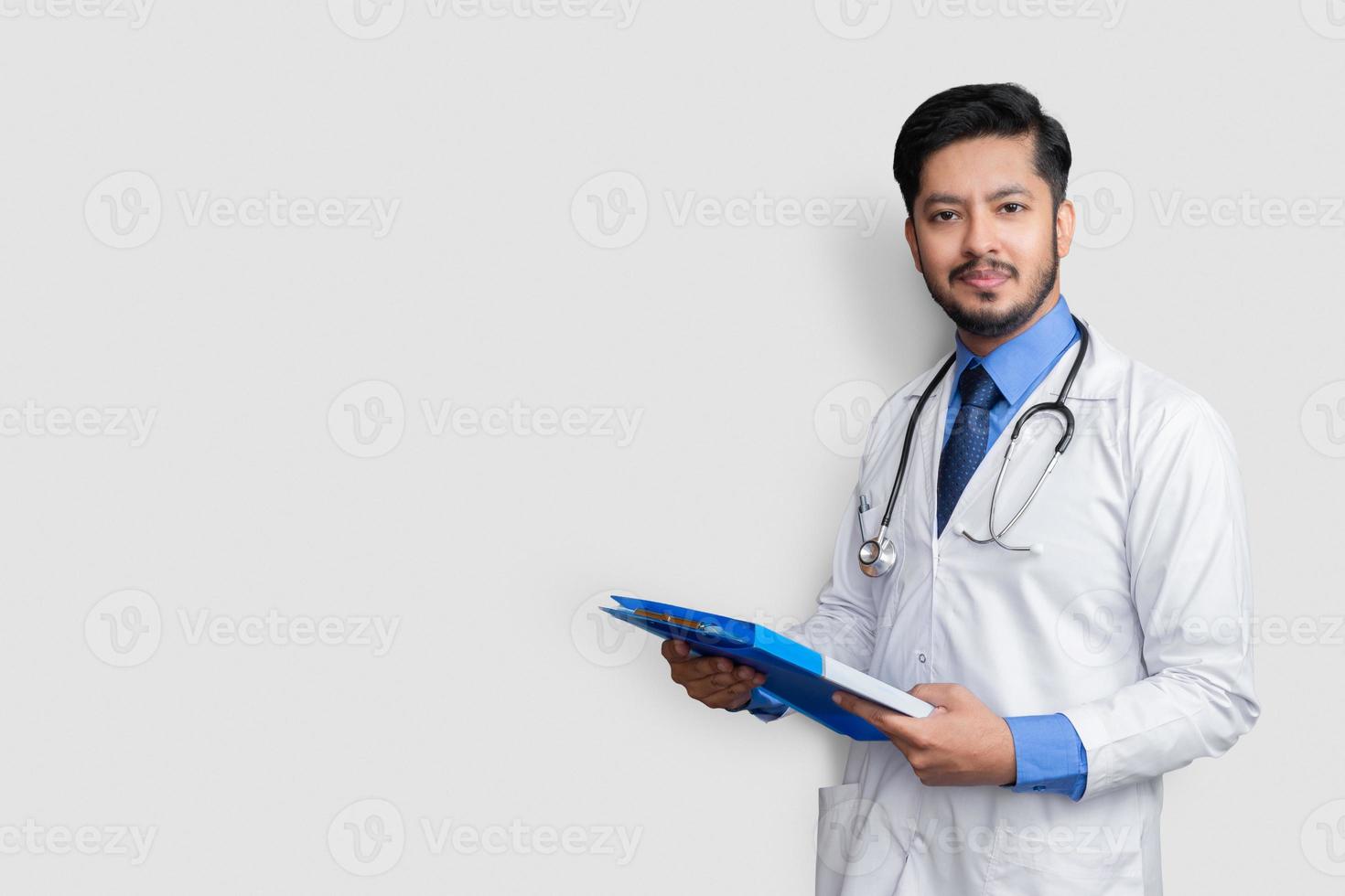 Doctor en bata de laboratorio sosteniendo el expediente del paciente o notas médicas mirando a la cámara, aislado sobre fondo blanco. foto