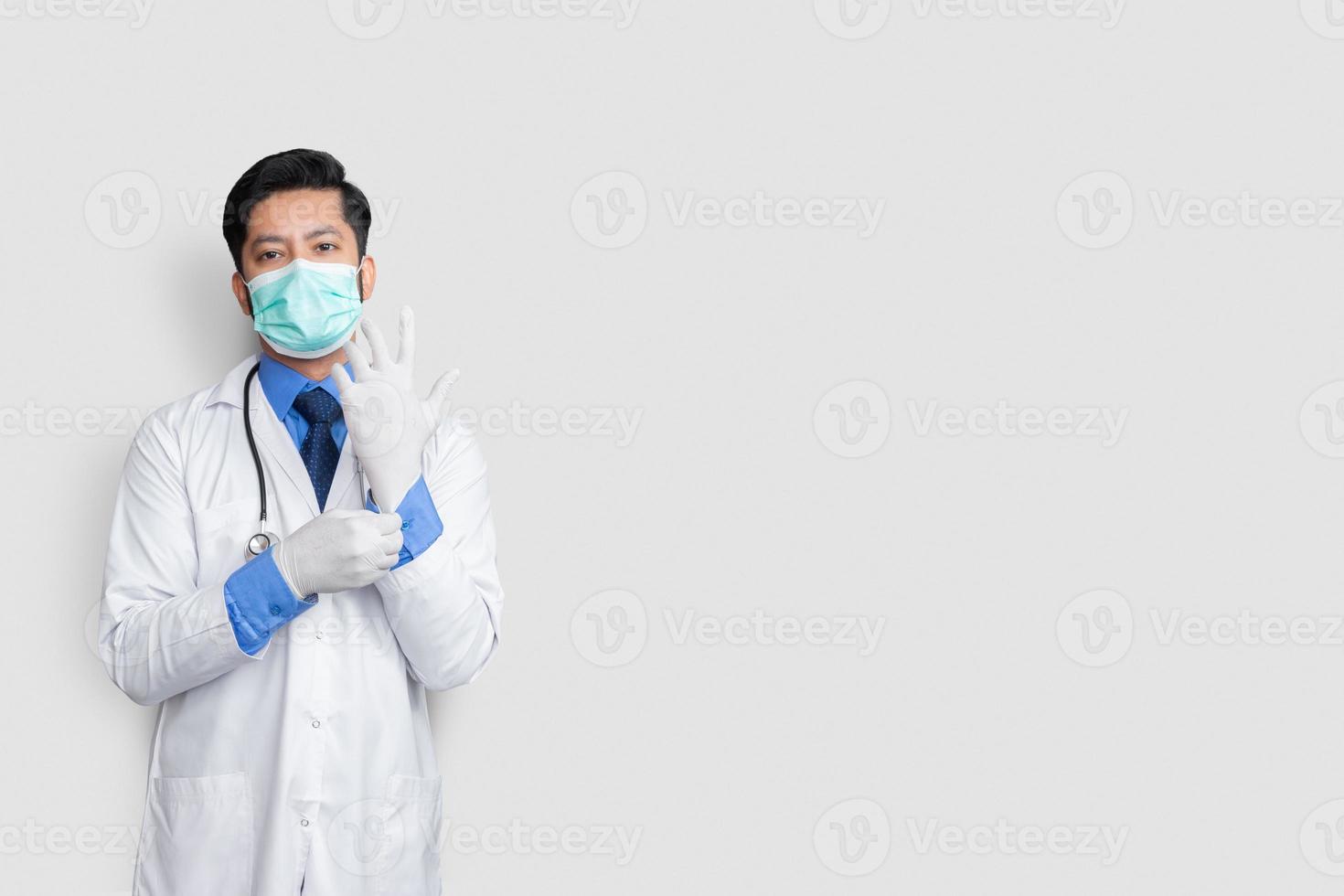 Pakistani doctor wearning gloves and stethoscope with mask on face. operation surgery preparation. photo