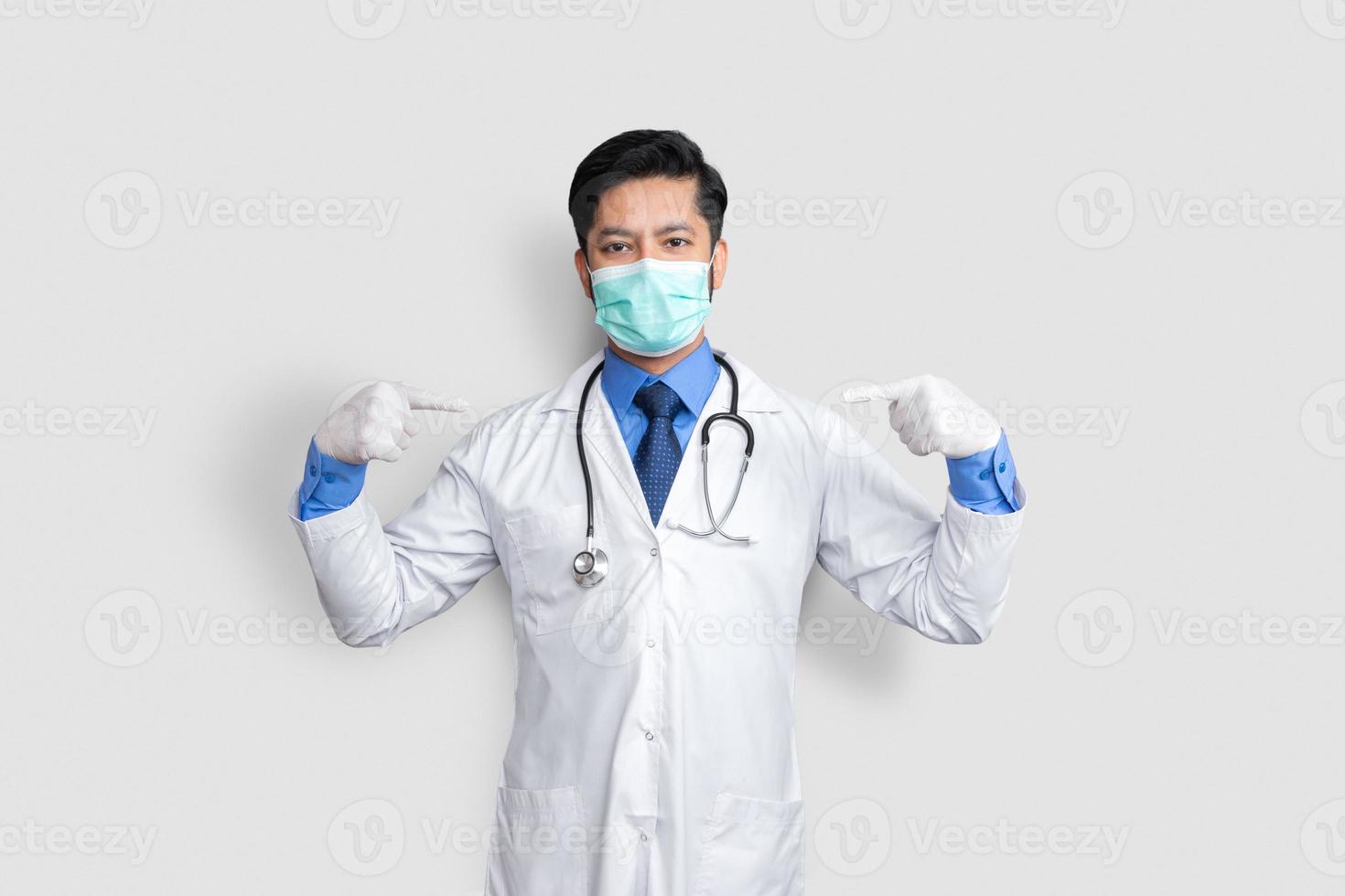 Handsome Pakistani doctor and stethoscope with mask on face, pointing oneself with fingers proud and happy. photo