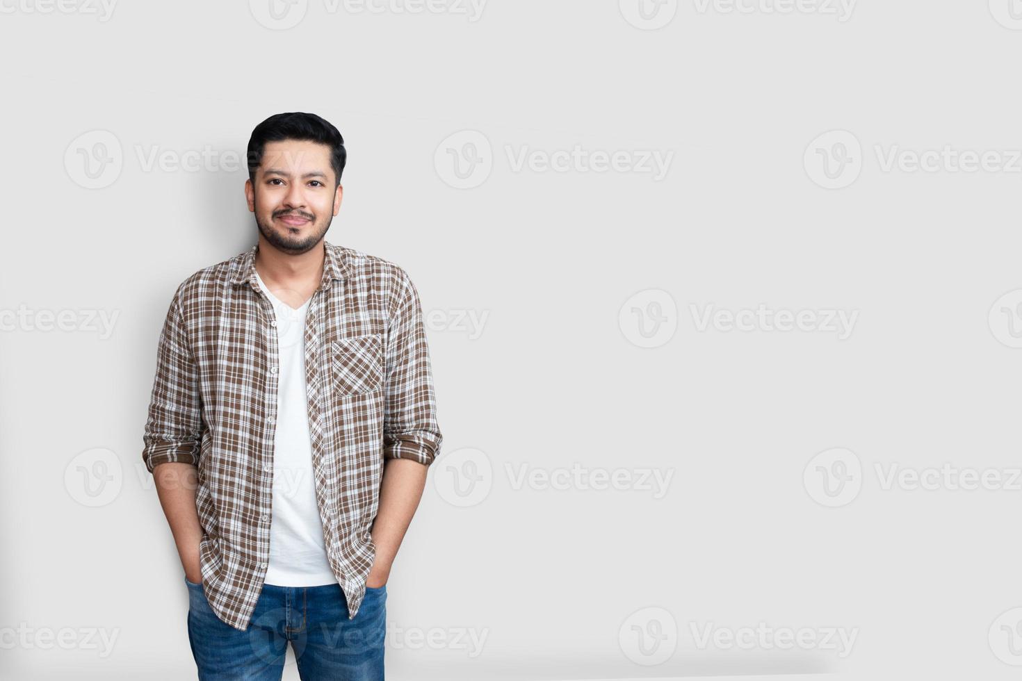 atractivo hermoso hombre asiático feliz positivo. Guapo chico paquistaní asiático vistiendo camisa a cuadros marrón con gran sonrisa aislado sobre fondo blanco. foto