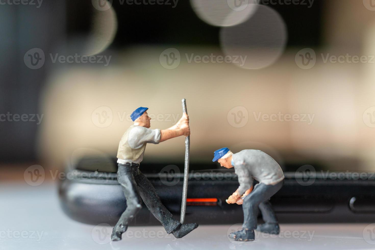 Trabajador de personas en miniatura con herramientas de reparación de teléfonos móviles foto