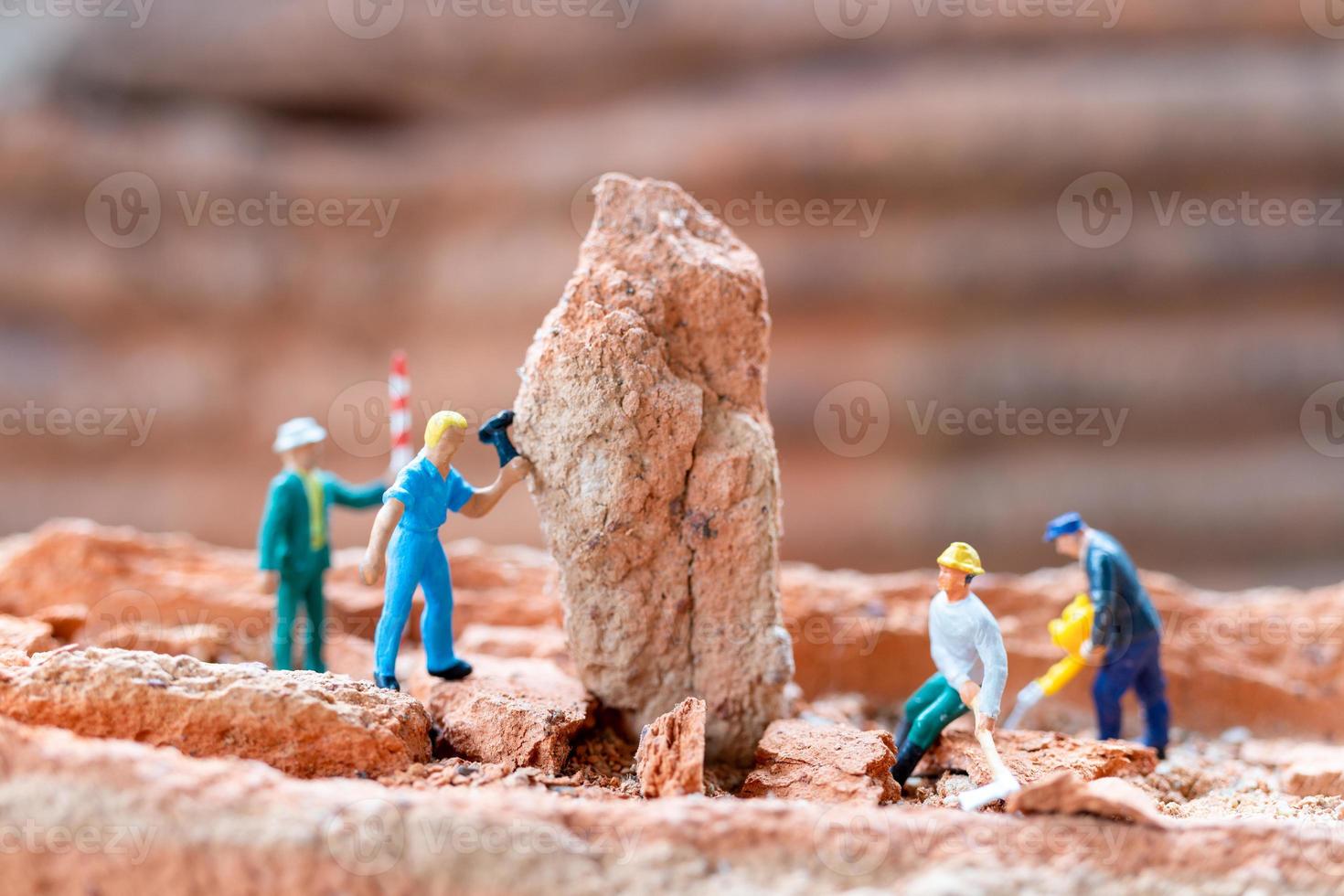 Equipo de trabajadores de personas en miniatura arreglando ladrillos durante la construcción de una casa foto