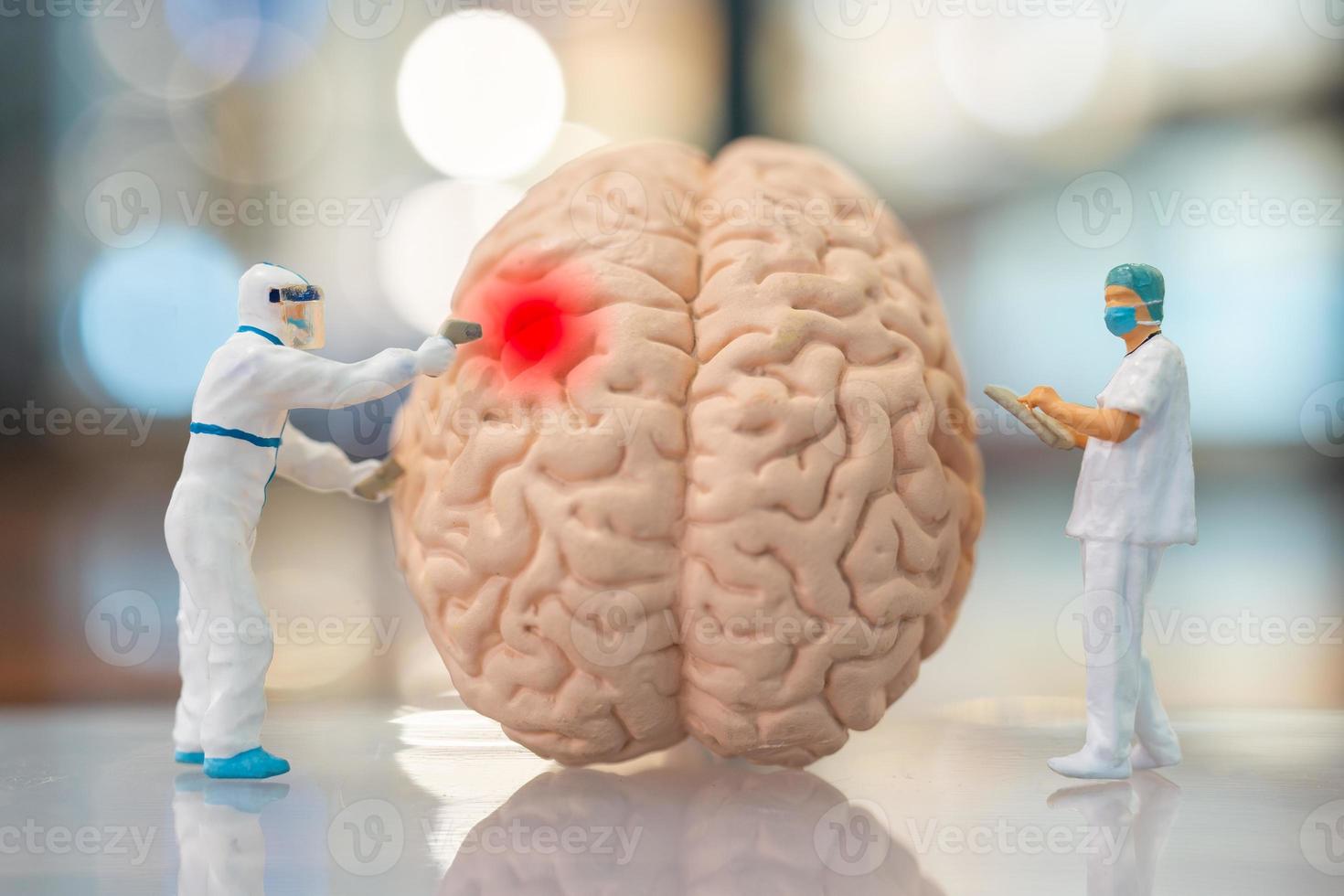 Personas en miniatura médico y enfermera observando y discutiendo sobre el cerebro humano. foto