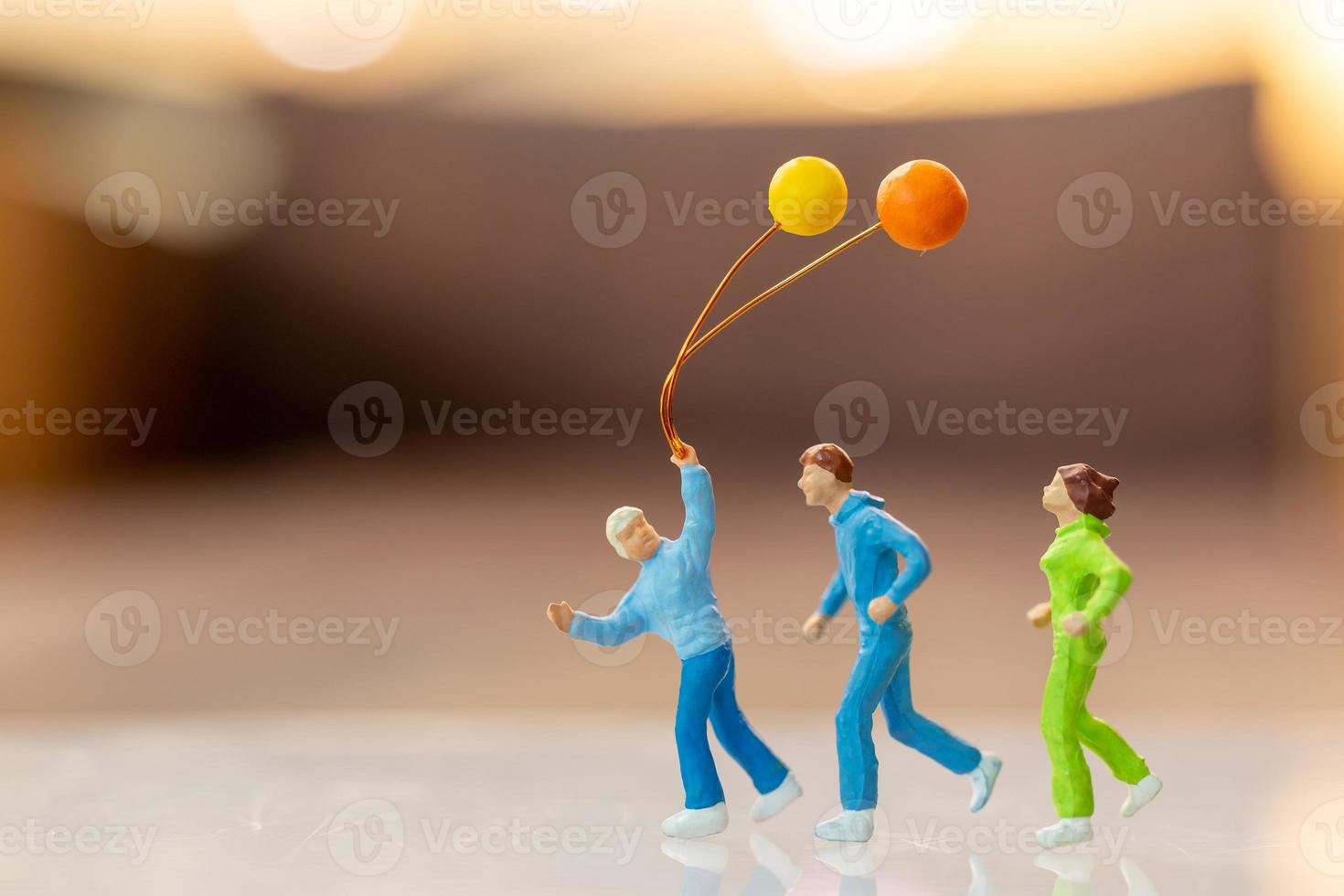 Gente en miniatura familia feliz corriendo y jugando con globo. foto