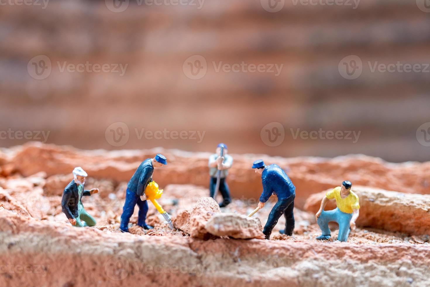 Equipo de trabajadores de personas en miniatura arreglando ladrillos durante la construcción de una casa foto