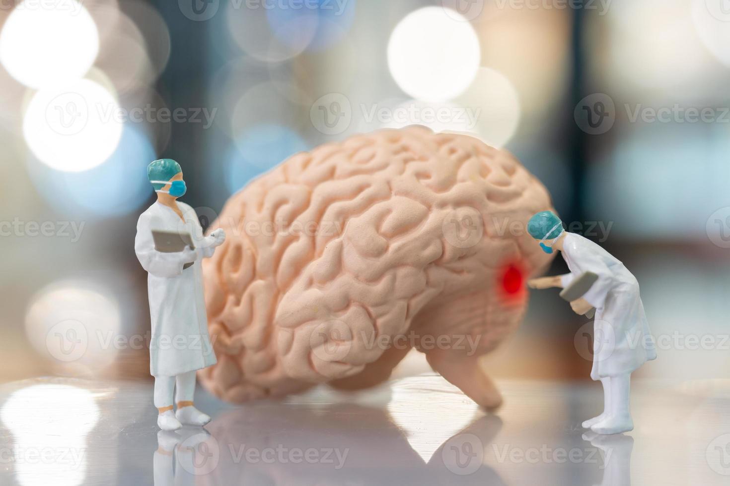 Personas en miniatura médico y enfermera observando y discutiendo sobre el cerebro humano. foto