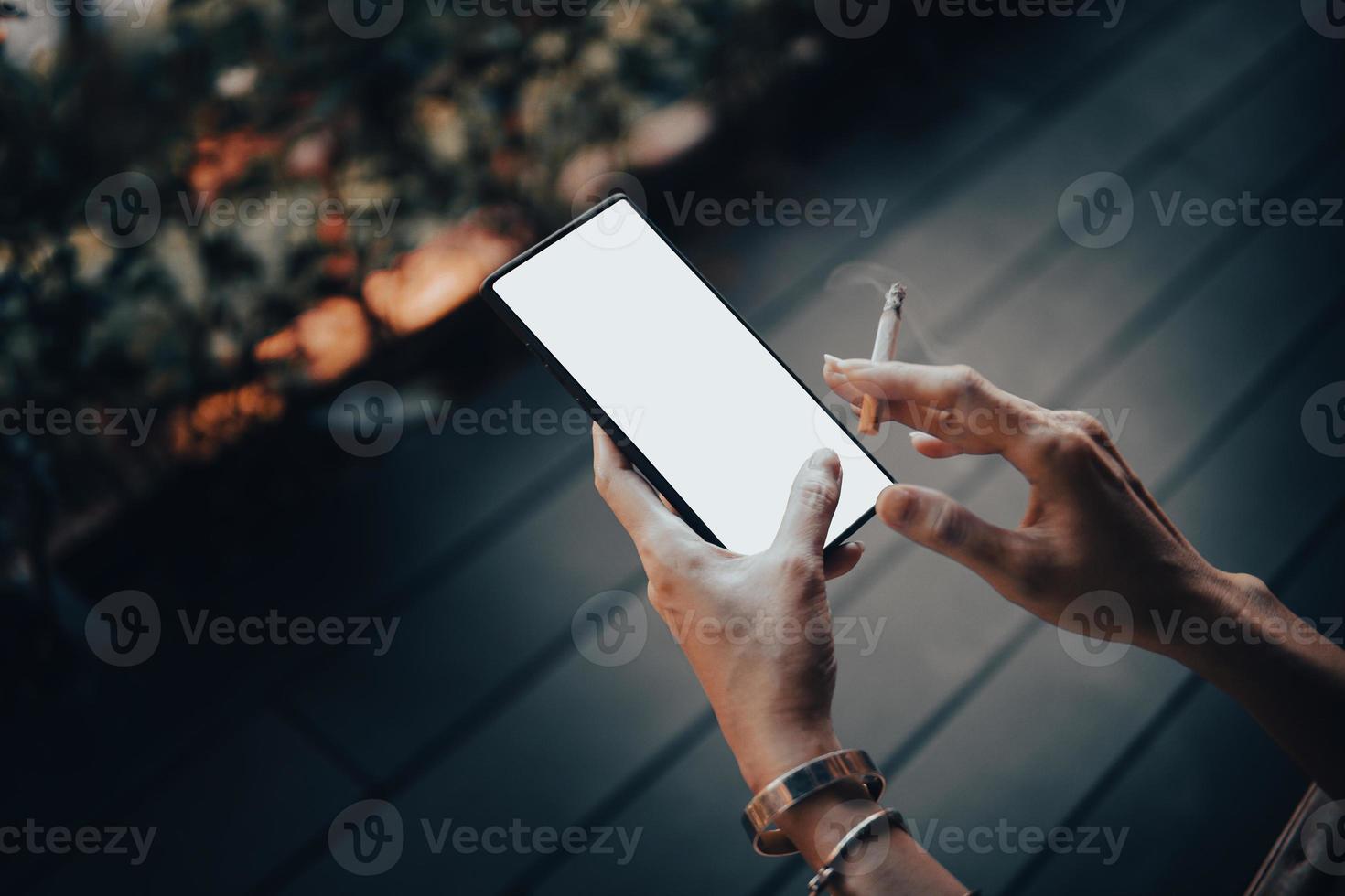 Woman's hands and smartphone with cigarettes. photo