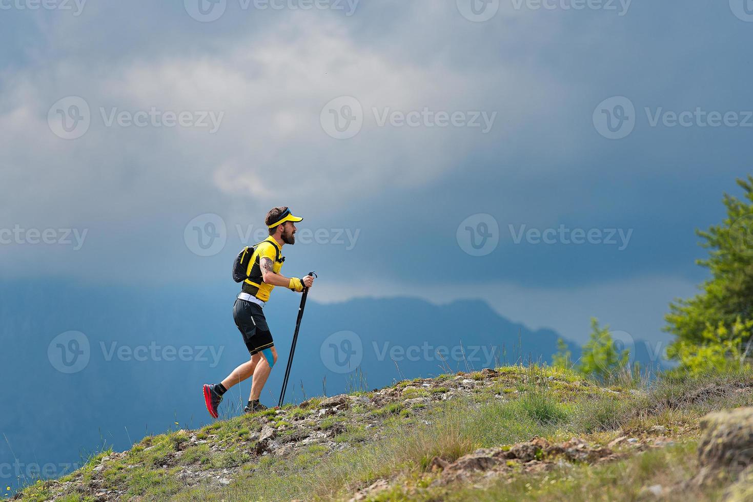 Male athlete climbs slope of mountain during mountain marathon training photo