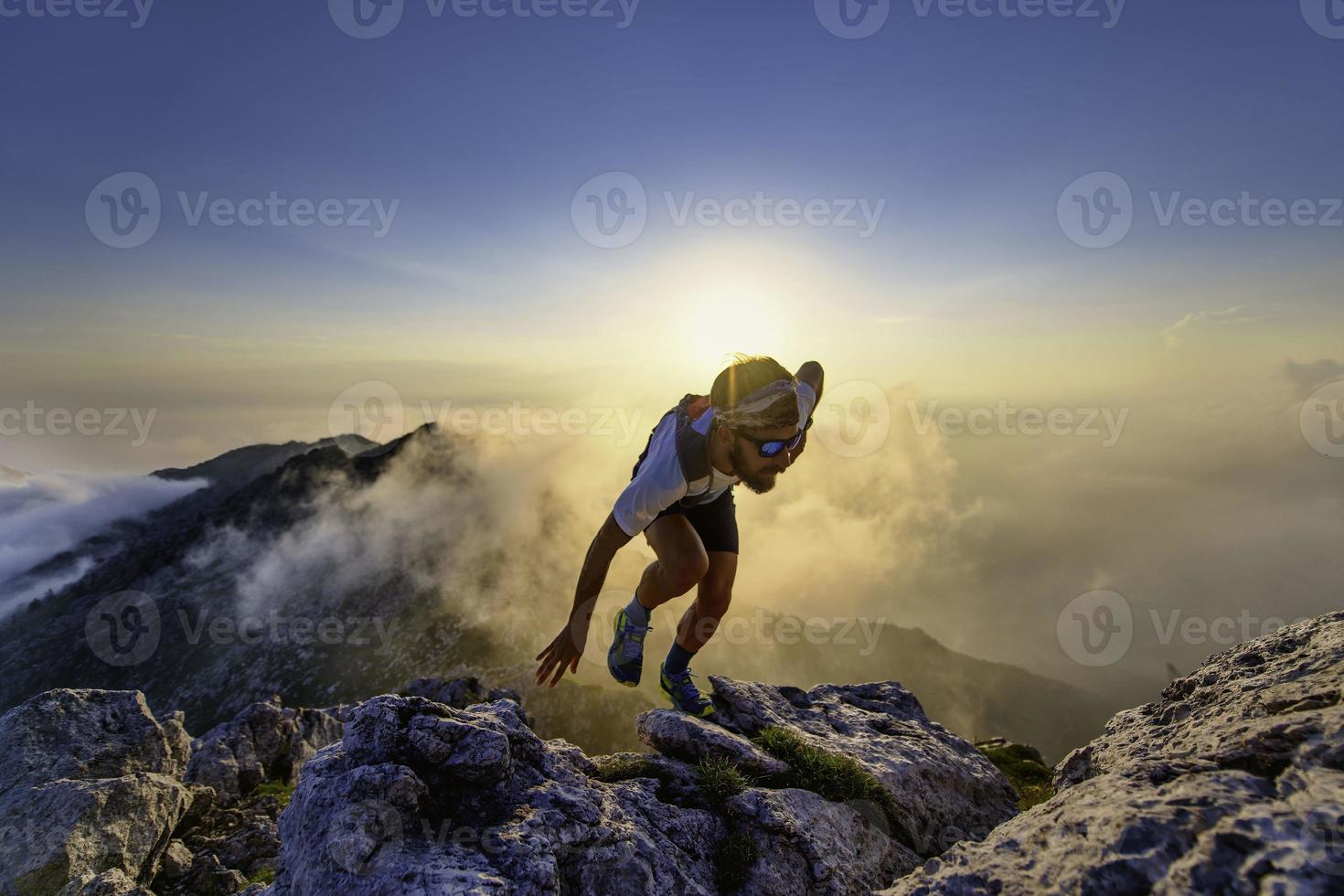 hombre corredor del cielo cuesta arriba en las rocas al atardecer foto