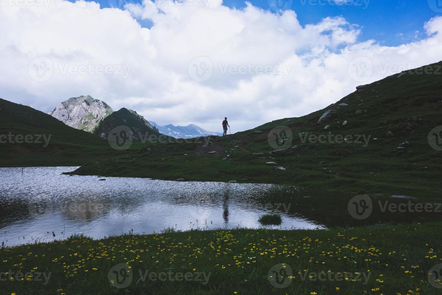 Mountain landscape with small lake and a person walking photo